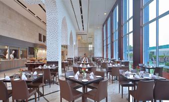 a large , modern restaurant with multiple dining tables and chairs arranged in an open layout at Radisson Hotel Agra