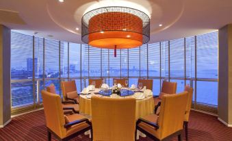 a large , round table with a chandelier in the center is surrounded by chairs and has a view of the ocean at Dusit Thani Pattaya