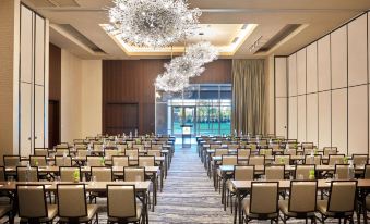 a large conference room with rows of chairs arranged in a semicircle , and a chandelier hanging from the ceiling at The Stella Hotel, Autograph Collection