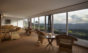 a spacious room with wicker chairs and a table , overlooking a mountainous landscape through large windows at Volcano House