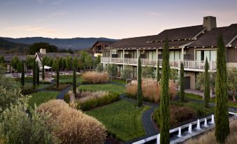 a beautiful hotel surrounded by lush greenery and mountains , with the sun setting in the background at Rosewood Sand Hill