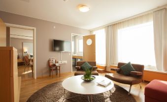 a living room with a white coffee table , brown leather chairs , and a large window at Scandic Linkoping City
