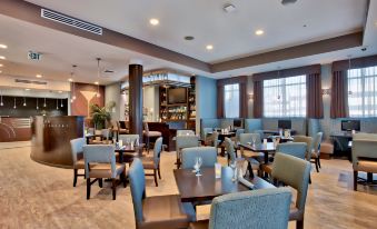a dining area in a hotel , with several tables and chairs arranged for guests to enjoy their meals at Hilton Garden Inn Irvine Spectrum Lake Forest
