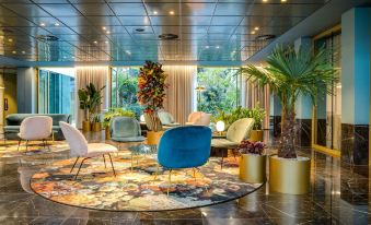 a modern hotel lobby with various seating options , including couches and chairs , as well as potted plants at NH Collection Antwerp Centre