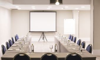 a conference room set up for a meeting , with chairs arranged in rows and a projector screen on the wall at Artiem Capri