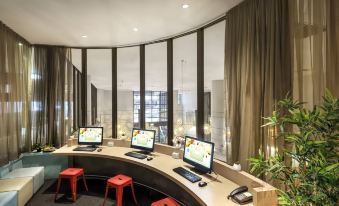 a modern office space with curved walls , large windows , and multiple computer workstations arranged in an office setting at Ibis Melbourne Hotel and Apartments