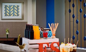 a dining table with a variety of food and drinks , including bottles , cups , and straws at Suites Birmingham