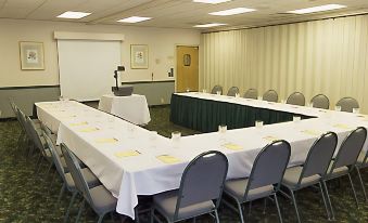 a conference room with a long table covered in white tablecloths and chairs arranged around it at Best Western Downtown Stuart