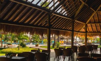 a wooden gazebo with thatched roof , providing shade and a view of the pool area at Pousada Praia Dos Carneiros