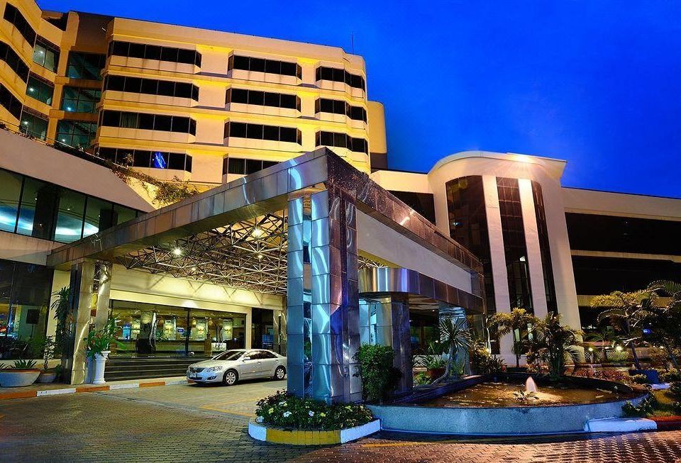 a modern hotel building with a blue and white color scheme , surrounded by trees and lit up at night at Chon Inter Hotel