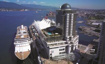aerial view of a large cruise ship docked at a port , surrounded by other boats and buildings at Pan Pacific Vancouver