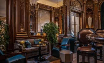 a luxurious living room with a large wooden headboard , blue couches , and multiple potted plants at Hotel the Peninsula Paris