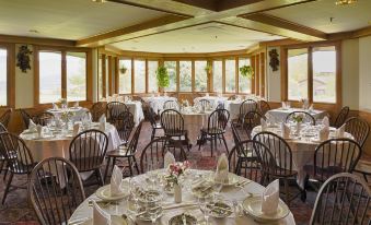a large dining room with multiple tables and chairs , all set for a formal dinner at Trapp Family Lodge