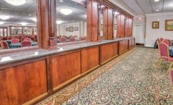 a long , wooden bar with a mirror on the wall and a large mirror above it at Ramada by Wyndham Metairie New Orleans Airport