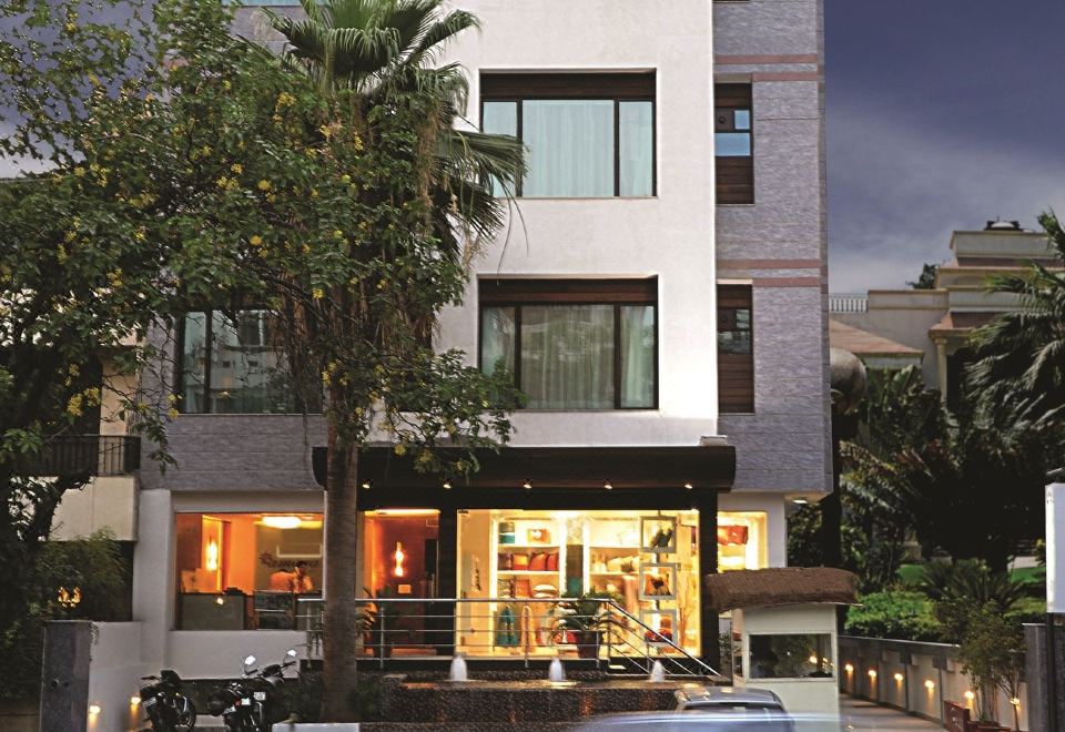 a modern building with a car parked in front and palm trees lining the street at Amara Hotel