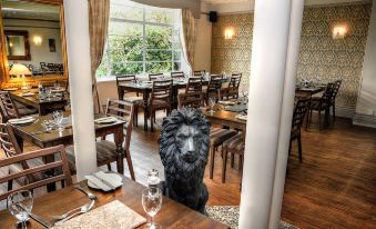 a lion statue is sitting in the corner of a dining room with tables and chairs at Lion Hotel & Studio Apartments
