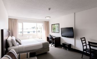 a modern hotel room with a large window , white walls , and a bed , as well as a tv , desk , and chair at St Ives Apartments