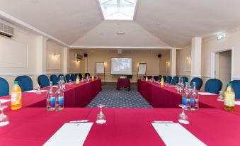 a conference room set up for a meeting , with multiple chairs arranged in rows and a projector on the wall at Best Western New Holmwood Hotel