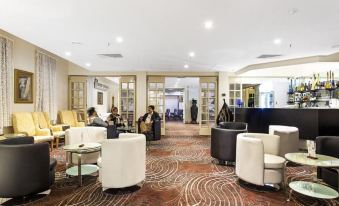 a large , well - lit lobby with several people sitting and standing around , enjoying the space at Mercure Maitland Monte Pio
