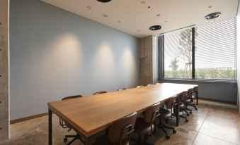 a large conference room with a wooden table and chairs arranged in a row , along with a window that overlooks the outdoors at Kawasaki King Skyfront Tokyu Rei Hotel