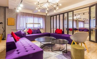 Guests have access to a colorful living room furnished with couches and tables, including matching colors to create a comfortable and inviting space for relaxation and socializing at Campanile Hotel (Shanghai Railway Station, People's Square)