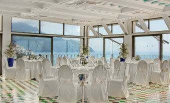 a large dining room with white tablecloths and chairs set up for a wedding reception at Hotel Miramalfi