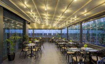 an outdoor dining area with tables and chairs , surrounded by a glass wall and ceiling at Golden Tulip Istanbul Bayrampasa