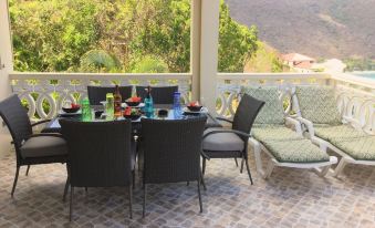 a patio table with chairs is set up on a balcony overlooking a mountainous landscape at Ocean View Villas