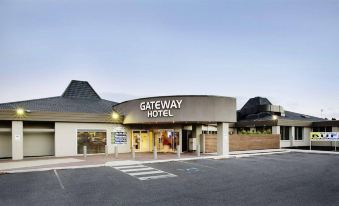 the entrance to the gateway hotel , with a large curved sign above the door and an urban landscape in the background at Nightcap at Gateway Hotel
