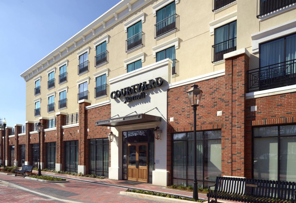"a brick building with a sign that says "" claremont - inn "" and a bench in front" at Courtyard LaGrange