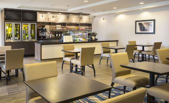a dining area with several tables and chairs , as well as a kitchen counter with a coffee machine at Courtyard Seattle North/Lynnwood Everett
