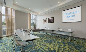 a conference room with a long table and chairs , a large screen on the wall , and framed pictures at Fairfield by Marriott San Salvador