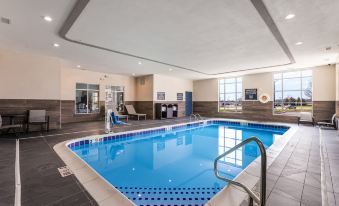 an indoor swimming pool with a blue water and white tiles , surrounded by chairs and tables at Four Points by Sheraton Elkhart
