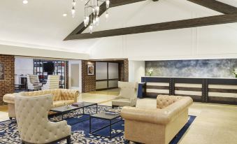 a spacious living room with high ceilings , multiple couches , and a dining table in the background at Delta Hotels by Marriott Baltimore Hunt Valley
