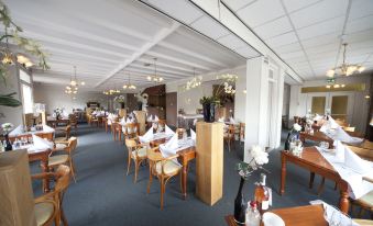 a large dining room with wooden tables and chairs arranged for a group of people at Fletcher Hotel Restaurant de Gelderse Poort