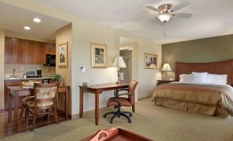 a hotel room with a desk , chairs , and a bed , along with a bedroom and bathroom visible at Homewood Suites by Hilton Rochester - Victor