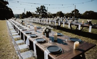 a long wooden table set for a wedding reception , with numerous plates and cutlery arranged neatly on the table at Ardeena