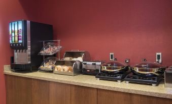 a dining area with a buffet table filled with a variety of food items , including sandwiches , salads , and desserts at TownePlace Suites by Marriott Champaign