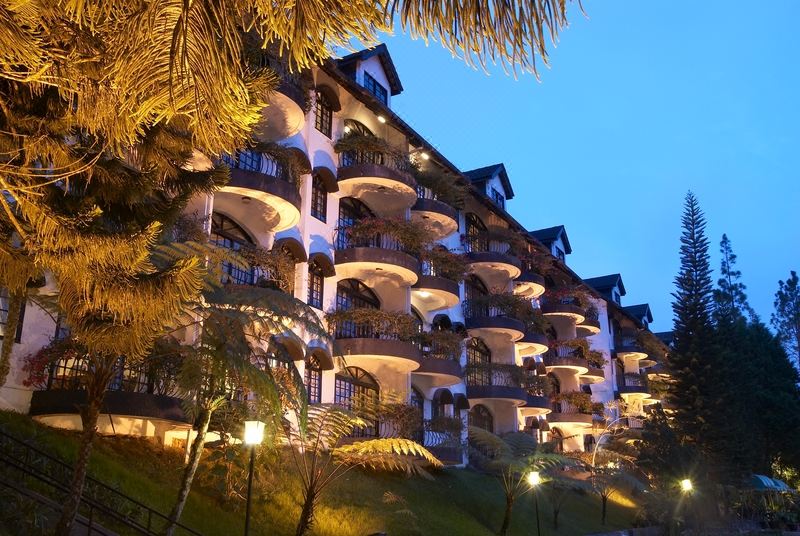 a large , multi - story building with balconies and palm trees in front of it at dusk at Strawberry Park Resort