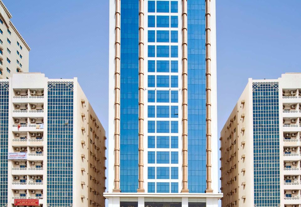 a tall building with a blue and white exterior is surrounded by other buildings in a city at Mangrove Hotel