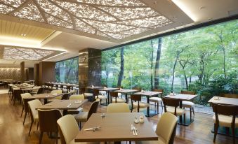 There is a restaurant with tables and chairs in front, featuring large windows that provide a view of the dining room area at Keio Plaza Hotel Tokyo