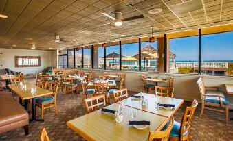 a large dining room with wooden tables and chairs arranged for a group of people to enjoy a meal together at Ramada Plaza by Wyndham Nags Head Oceanfront