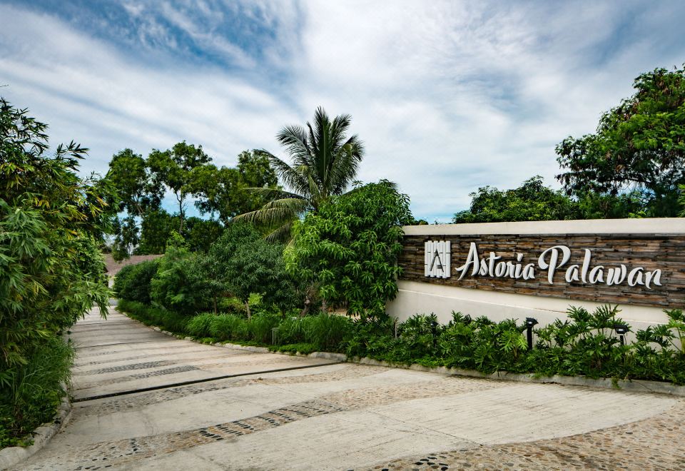 "a stone wall with the words "" astonia park "" written on it , surrounded by greenery and trees" at Astoria Palawan