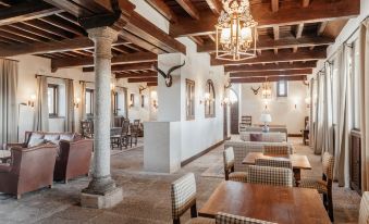 a spacious , well - lit restaurant with wooden beams and white walls , featuring multiple dining tables and chairs at Parador de Gredos