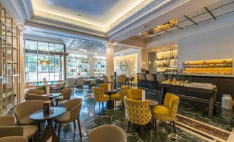 a luxurious hotel lobby with marble floors , high ceilings , and a bar area , filled with comfortable seating and dining options at NH Madrid Nacional
