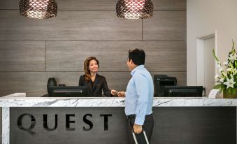 "a man and a woman are standing in front of a reception desk with the word "" guest "" on it" at Quest Kings Park