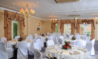 a large , elegant banquet hall with multiple dining tables and chairs set up for a formal event at Coulsdon Manor Hotel and Golf Club