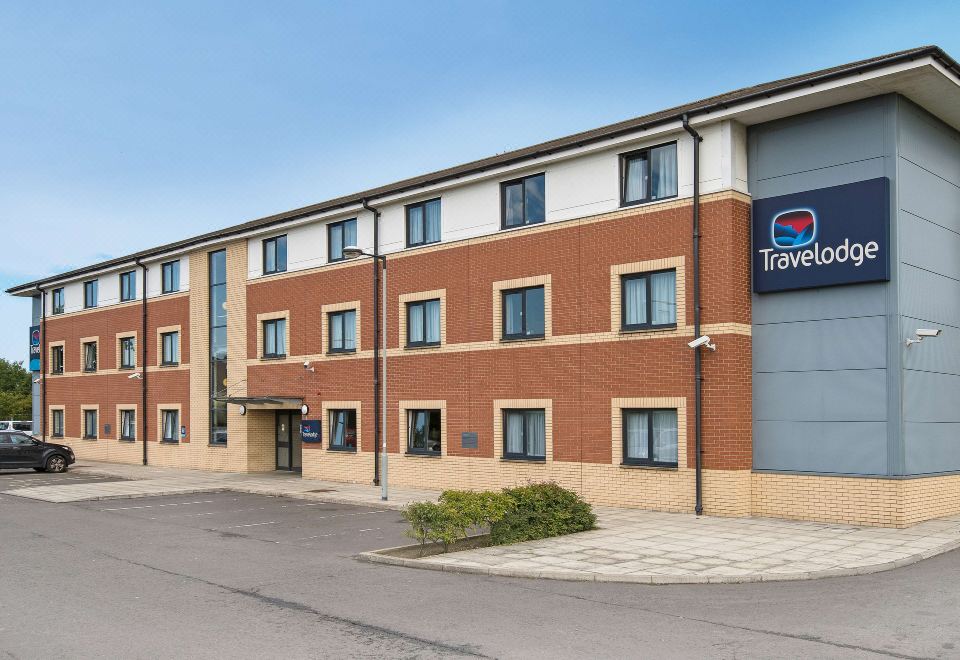 "a modern hotel building with a blue sign that reads "" travelodge "" and a clear sky in the background" at Travelodge Glenrothes
