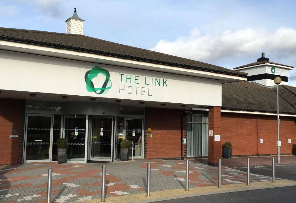 "a brick building with a sign that reads "" the link hotel "" prominently displayed on the front of the building" at Link Hotel