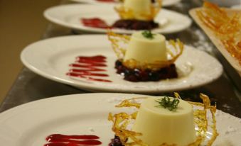 a row of plates with desserts on them are lined up with red sauce and garnish at Grange Burn Motel